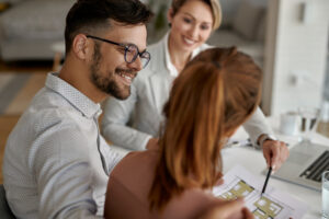 Tout savoir sur Courtier immobilier ICC Finance Pret Immobilier Jeune couple souriant pendant leur rendez-vous avec un courtier en pret immobilier